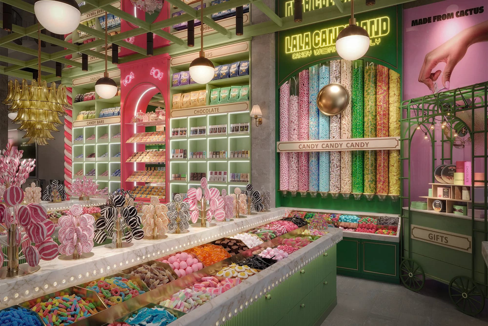 A dark green wall of tall glass gravity tubes filled with candy in every colour under the yellow neon LaLa Candyland sign, beside a green iron gift cart.